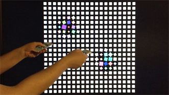 User demonstrating substrate capabilities by pointing two iPhones at a screen, distorting a grid of squares according to the movement of each device