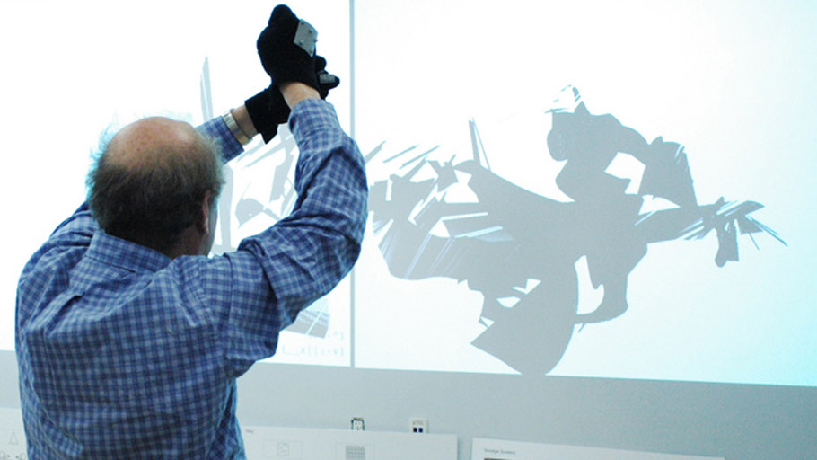 Man holds hands over his head with gestural tracking gloves, making virtual marks with a squeezing gesture